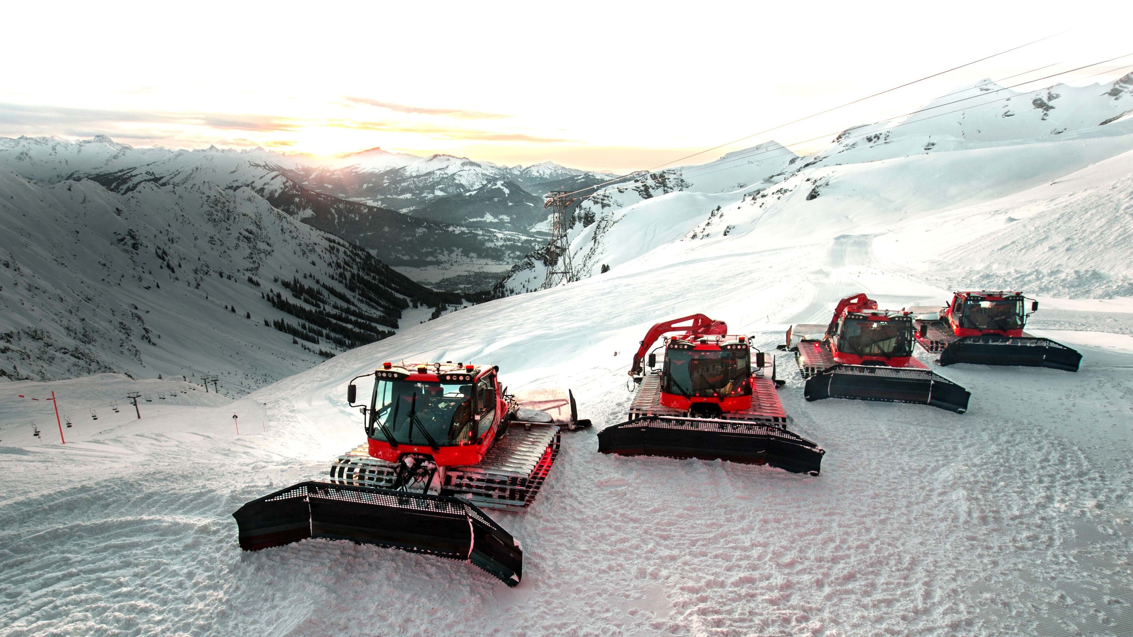 Four PistenBully 600 in front of a beautiful mountain range.