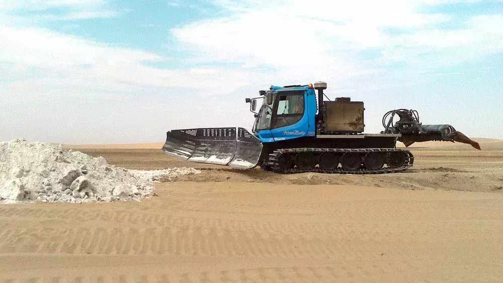 PistenBully 300 Polar GreenTech déplaçant du gravier.