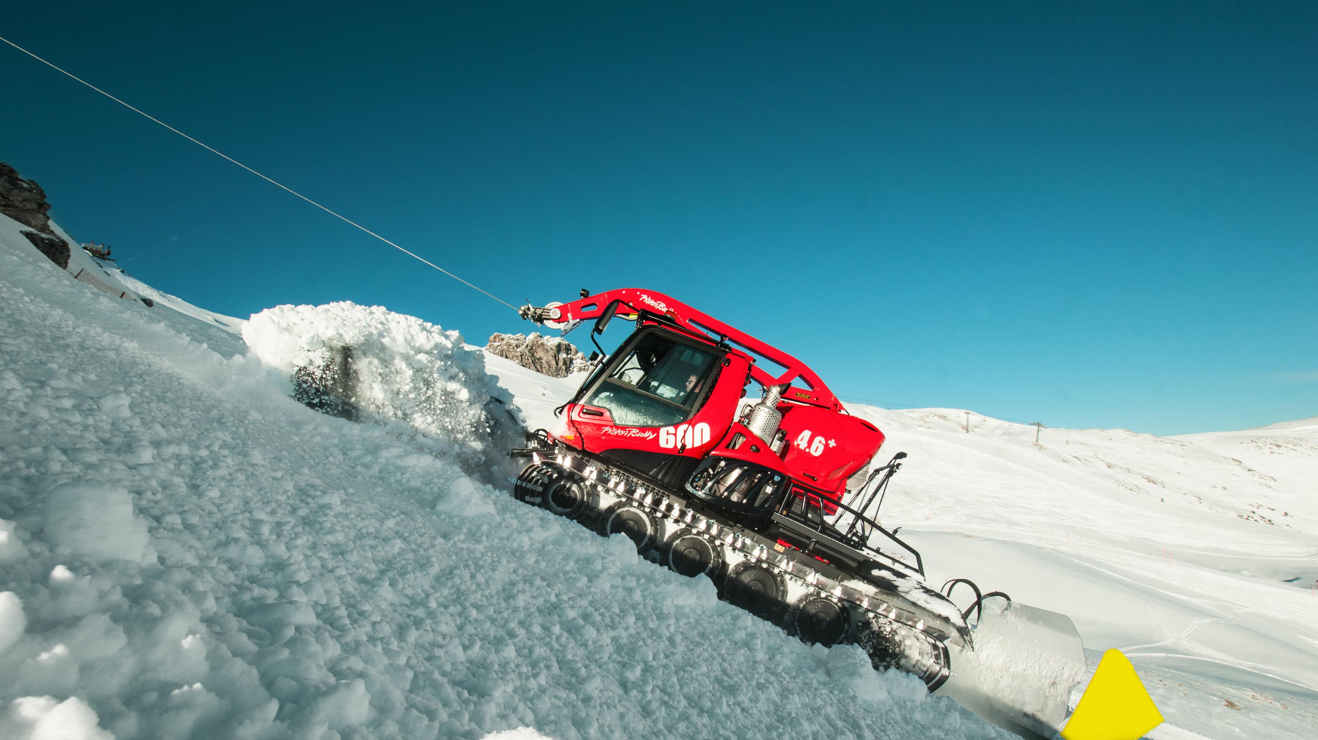 Le PistenBully 600 W se hisse en haut de la montagne.