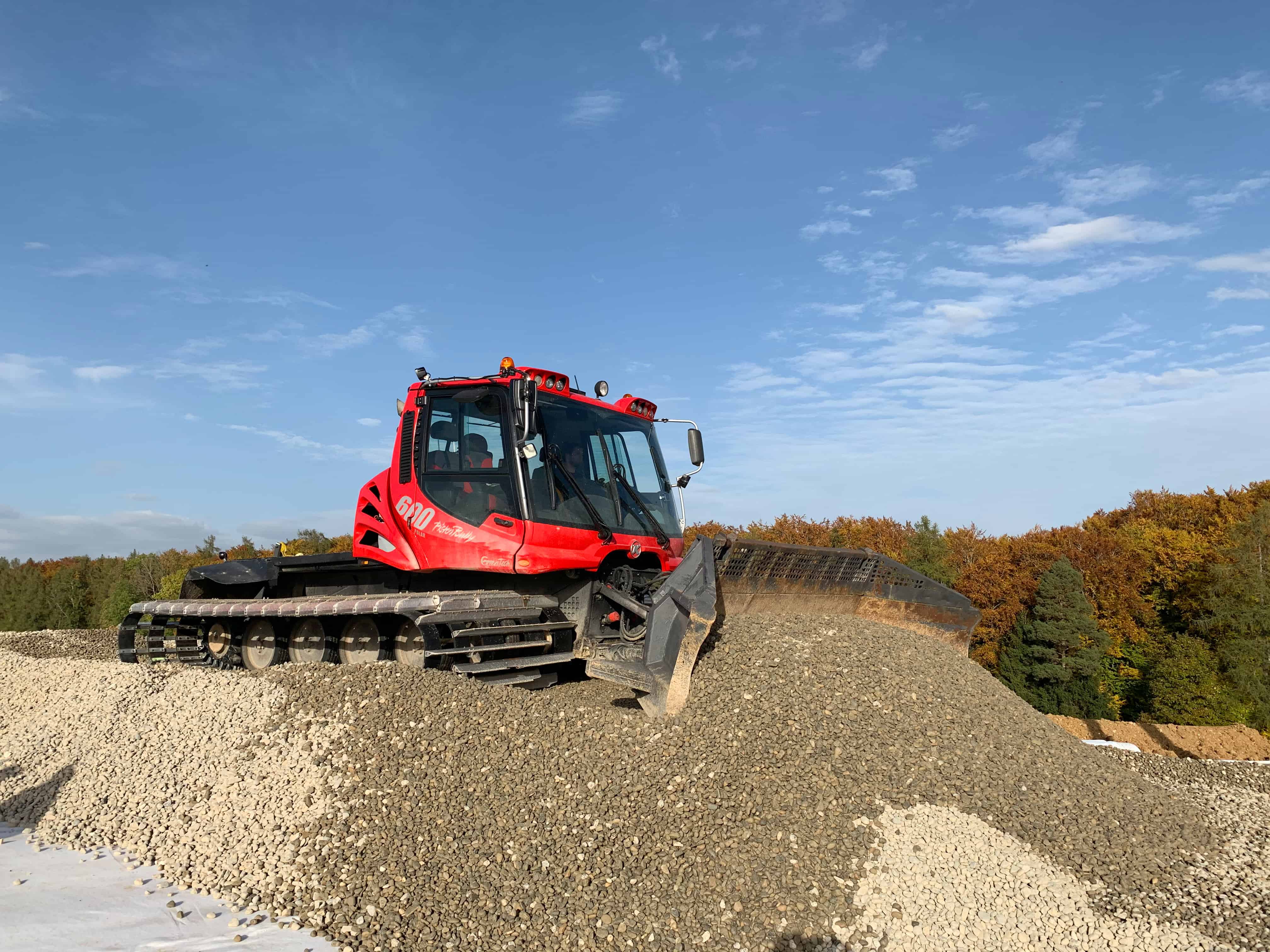 PistenBully 600 Polar GreenTech déplaçant du gravier.